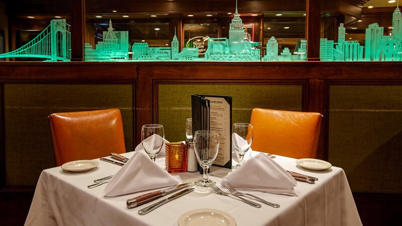 Table set up in Palm room with lit up New York City skyline partition